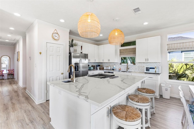 kitchen featuring a kitchen island, white cabinets, a sink, and stainless steel refrigerator with ice dispenser