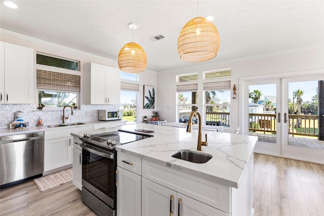 kitchen featuring stainless steel appliances, a center island with sink, a sink, and visible vents