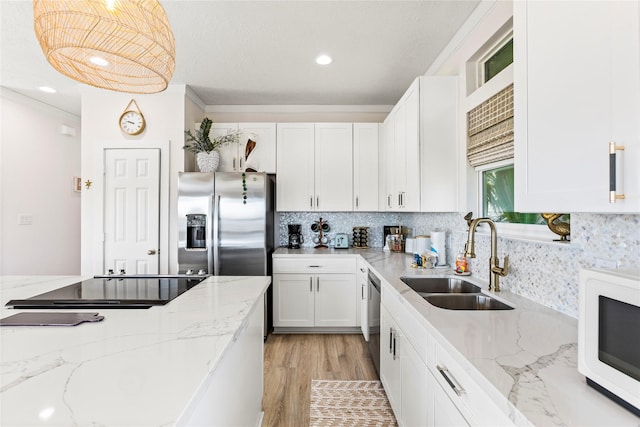 kitchen with decorative backsplash, appliances with stainless steel finishes, light stone countertops, white cabinetry, and a sink