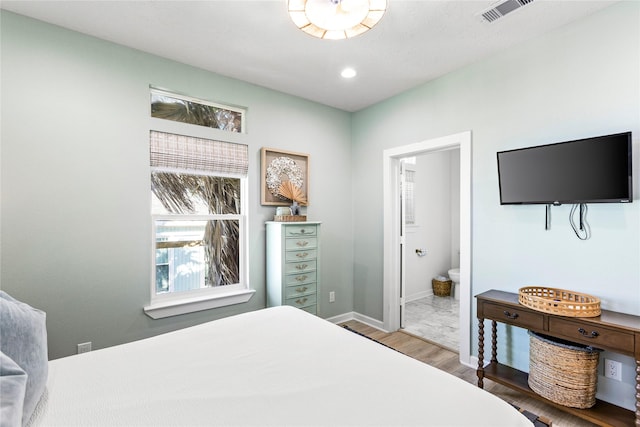 bedroom featuring recessed lighting, wood finished floors, visible vents, baseboards, and ensuite bath