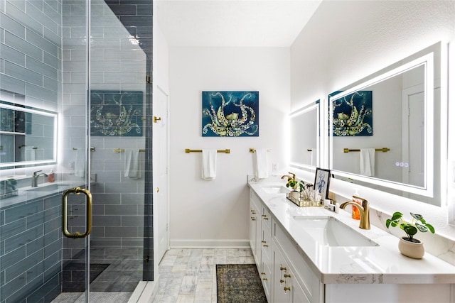 bathroom featuring double vanity, a stall shower, a sink, and baseboards