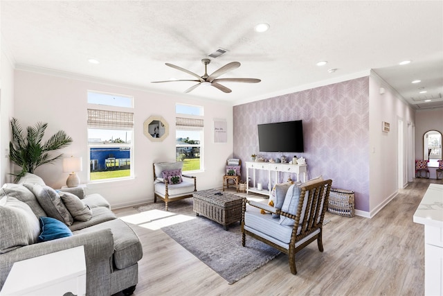 living area with visible vents, crown molding, baseboards, and wallpapered walls