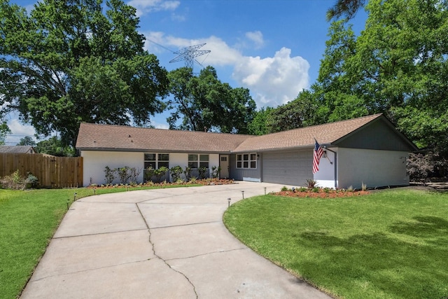 ranch-style house featuring a front lawn, driveway, an attached garage, and fence