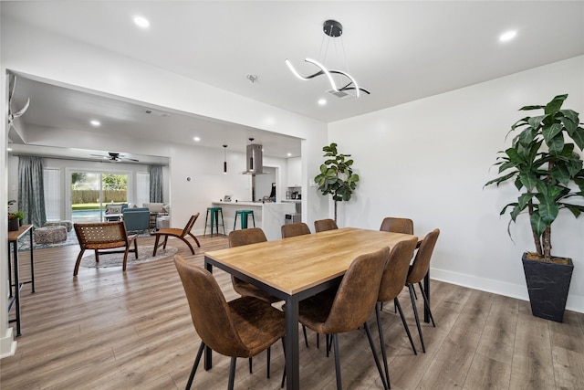 dining area with baseboards, recessed lighting, an inviting chandelier, and light wood-style floors