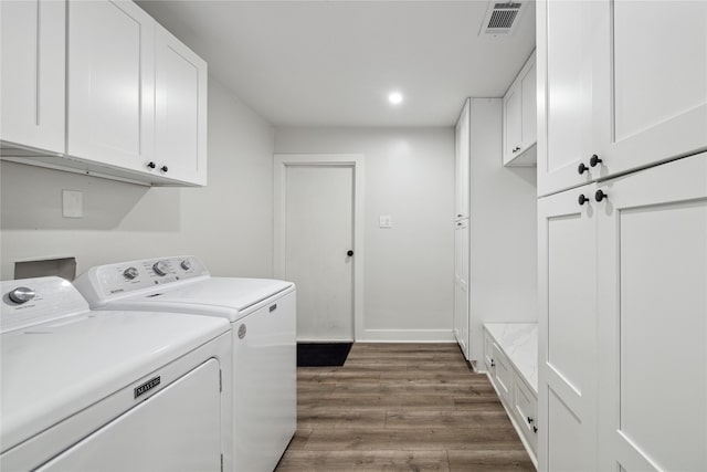 laundry room featuring dark wood-style flooring, cabinet space, visible vents, washer and dryer, and baseboards