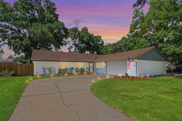 ranch-style home with a garage, fence, concrete driveway, and a front yard