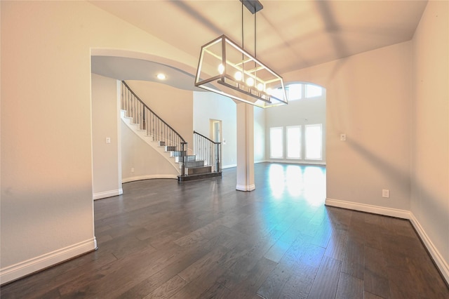 interior space with dark wood-style flooring, decorative columns, baseboards, and stairs