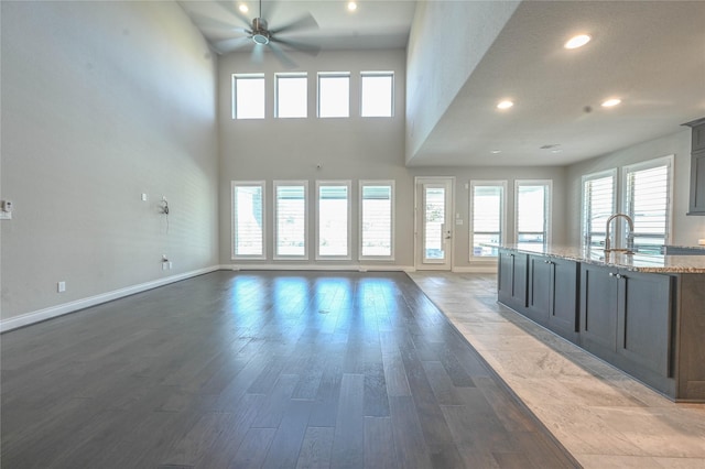 unfurnished living room with a ceiling fan, baseboards, wood finished floors, and recessed lighting