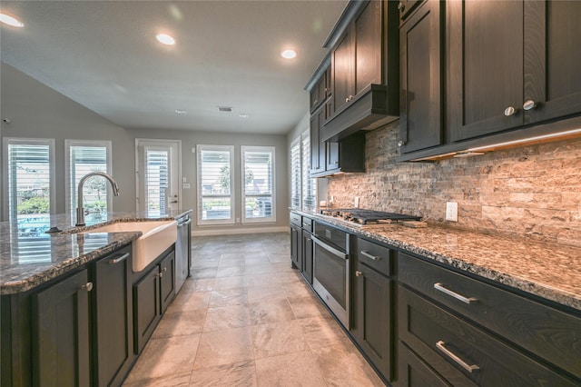 kitchen featuring stainless steel appliances, tasteful backsplash, visible vents, a sink, and dark stone counters