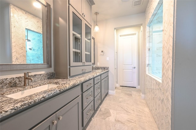 bathroom with double vanity, baseboards, visible vents, and a sink