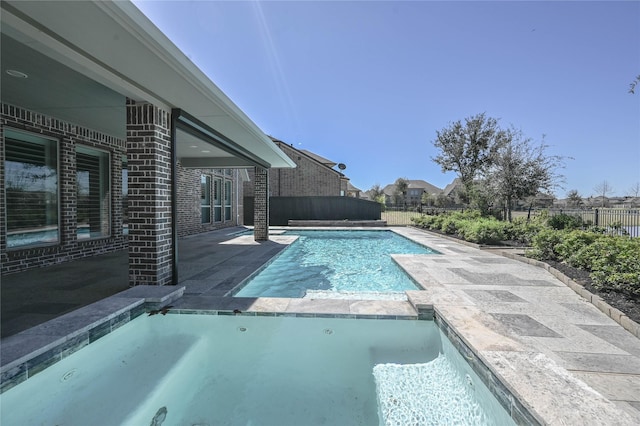 view of pool featuring a patio area, a fenced backyard, and a pool with connected hot tub