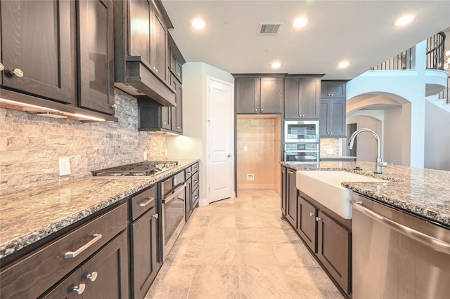 kitchen with light stone countertops, visible vents, stainless steel appliances, and a sink