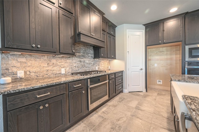 kitchen with appliances with stainless steel finishes, dark stone counters, and dark brown cabinets