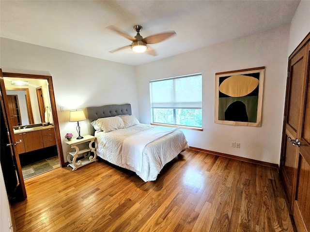 bedroom featuring ceiling fan, baseboards, ensuite bath, and hardwood / wood-style flooring