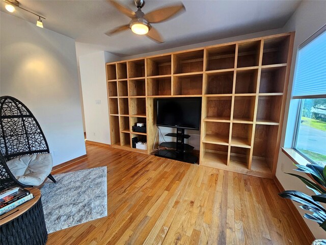 living room featuring baseboards, wood finished floors, and a ceiling fan