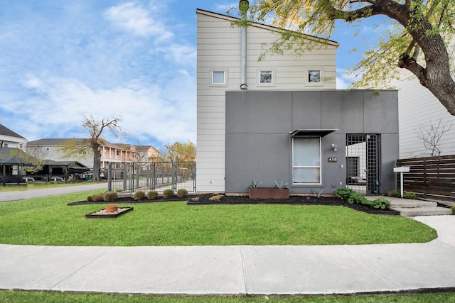 view of front of home featuring stucco siding, a front lawn, and fence