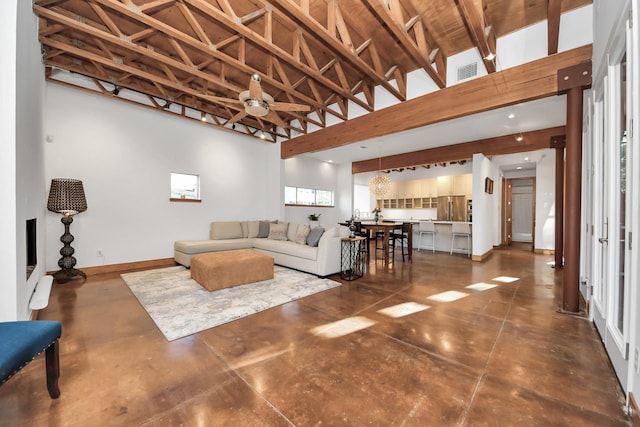 living area featuring visible vents, concrete floors, ceiling fan, baseboards, and a high ceiling