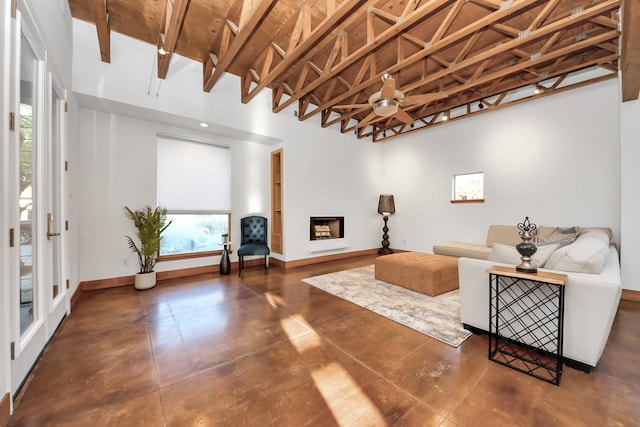 living area with a ceiling fan, a fireplace, baseboards, and concrete flooring