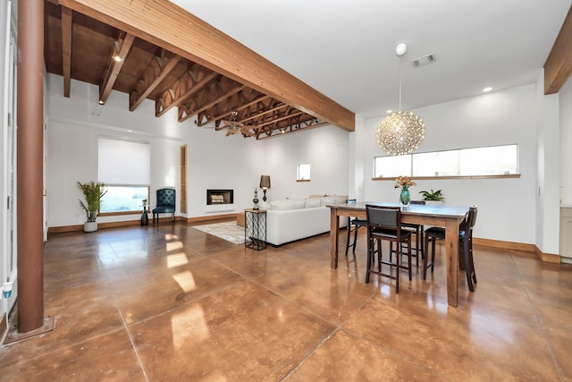 dining area with beamed ceiling, a fireplace, concrete flooring, and baseboards