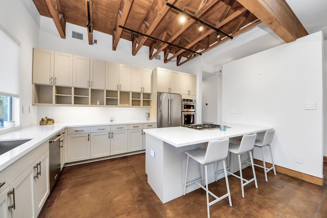 kitchen with a kitchen bar, light countertops, concrete flooring, appliances with stainless steel finishes, and open shelves