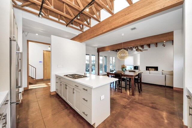 kitchen with stainless steel appliances, beamed ceiling, open floor plan, and a fireplace