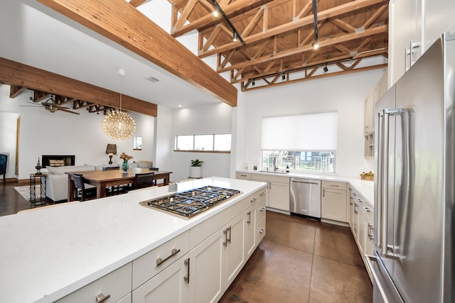 kitchen with beamed ceiling, open floor plan, light countertops, appliances with stainless steel finishes, and white cabinets