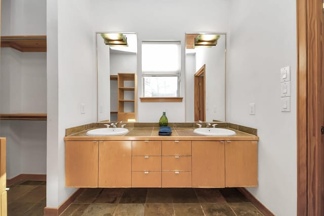 full bathroom featuring double vanity, baseboards, and a sink