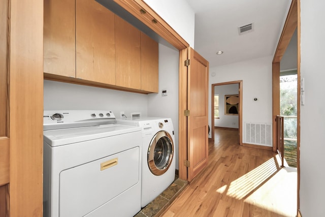 clothes washing area featuring visible vents, cabinet space, independent washer and dryer, and light wood finished floors