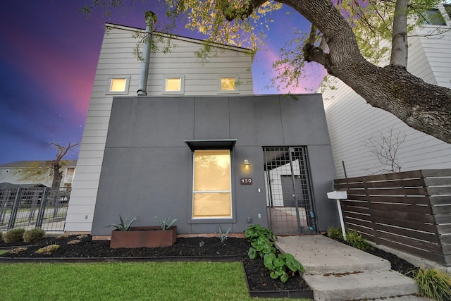 view of front of home with stucco siding, fence, and a gate