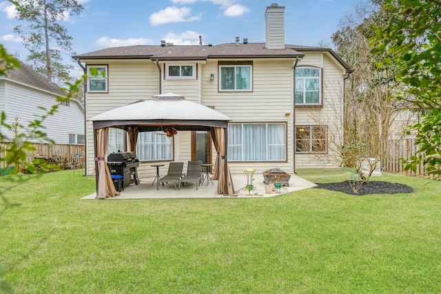 back of property featuring a patio, a fenced backyard, a chimney, a gazebo, and a lawn