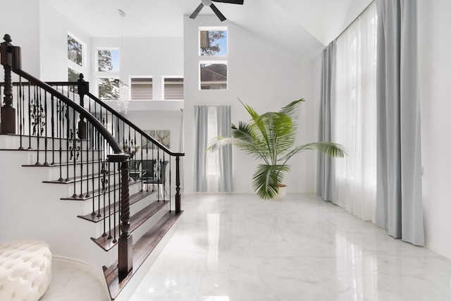 staircase featuring a high ceiling, marble finish floor, and ceiling fan