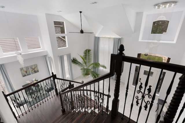 stairs with visible vents, lofted ceiling, wood finished floors, and a ceiling fan