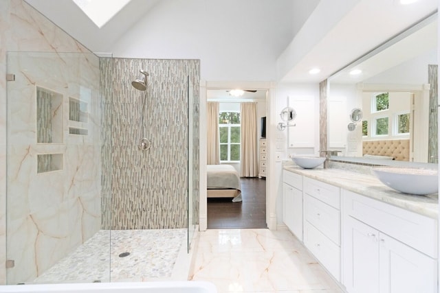 ensuite bathroom featuring lofted ceiling with skylight, marble finish floor, a sink, ensuite bath, and double vanity