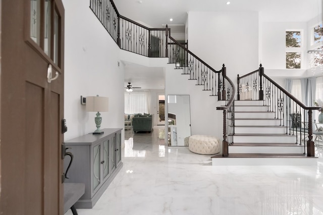 entryway with stairs, a high ceiling, marble finish floor, and a wealth of natural light