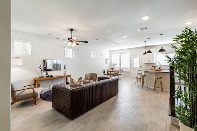 living room featuring a ceiling fan, light wood-type flooring, and visible vents