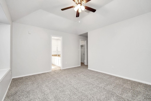 spare room with carpet, visible vents, a ceiling fan, vaulted ceiling, and baseboards