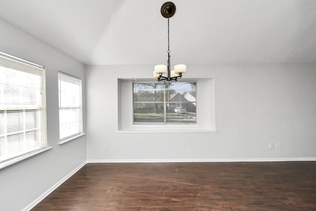 unfurnished dining area with vaulted ceiling, an inviting chandelier, wood finished floors, and baseboards