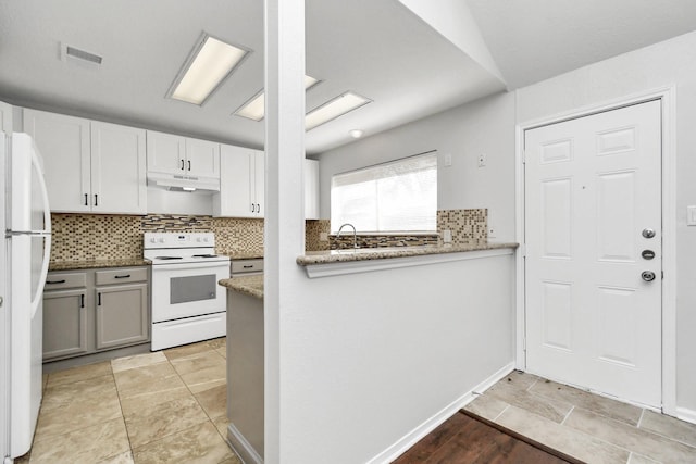 kitchen with light stone counters, tasteful backsplash, visible vents, white appliances, and under cabinet range hood