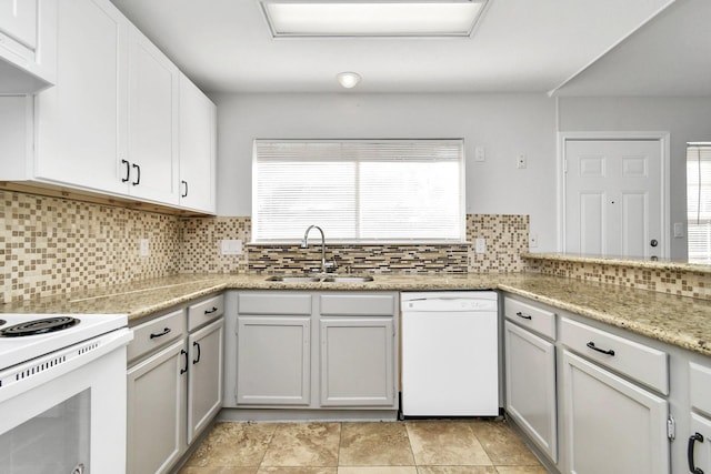 kitchen featuring white appliances, tasteful backsplash, under cabinet range hood, and a sink