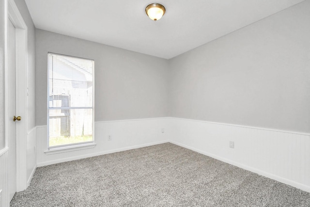 carpeted spare room with wainscoting