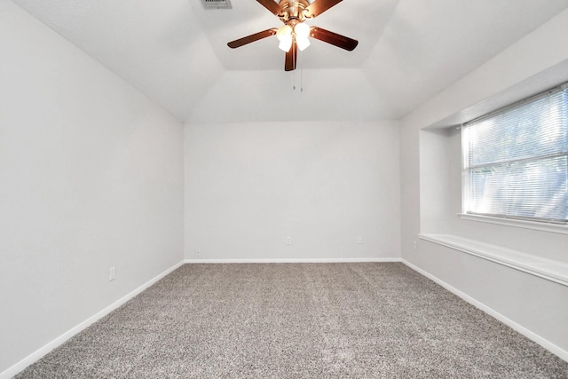 spare room with carpet flooring, vaulted ceiling, visible vents, and baseboards