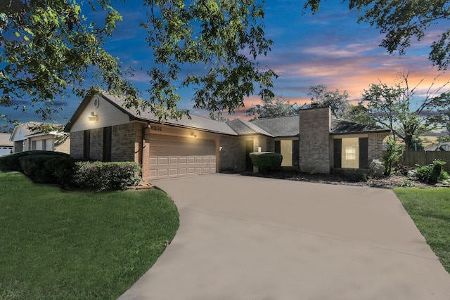 view of front of property featuring driveway, brick siding, a lawn, and an attached garage