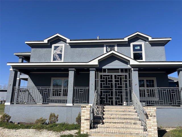 view of front of house with stairs, a porch, and stucco siding