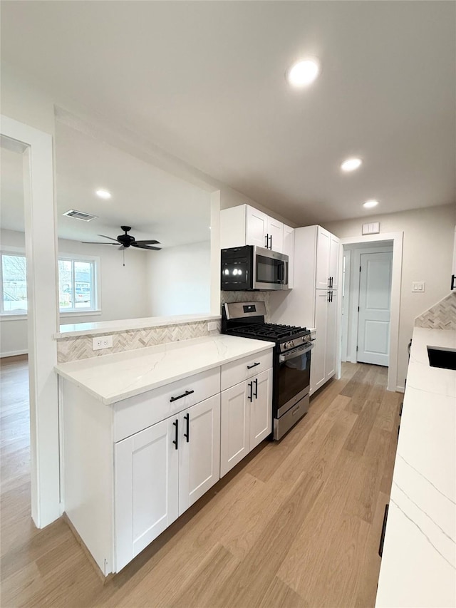 kitchen featuring stainless steel appliances, light wood-type flooring, visible vents, and white cabinets