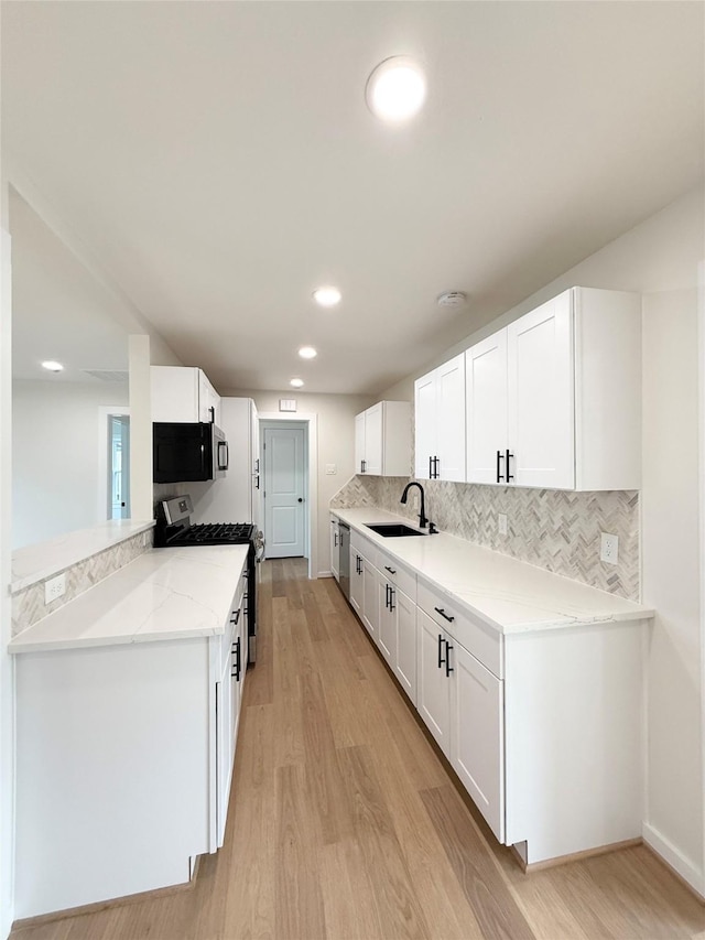 kitchen with stainless steel appliances, light wood-style floors, white cabinets, and a sink