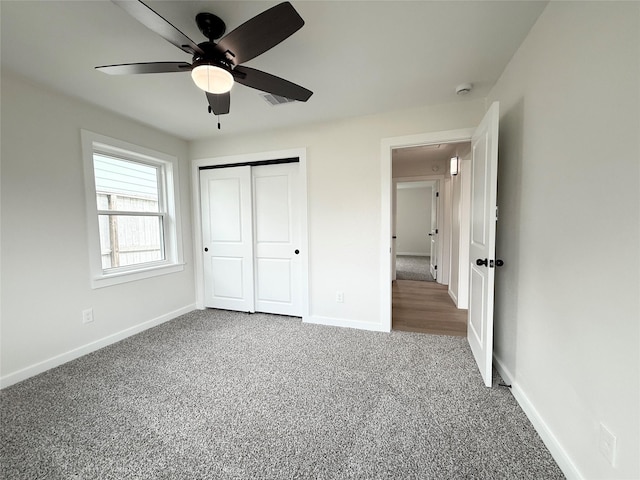 unfurnished bedroom featuring carpet flooring, a ceiling fan, visible vents, baseboards, and a closet