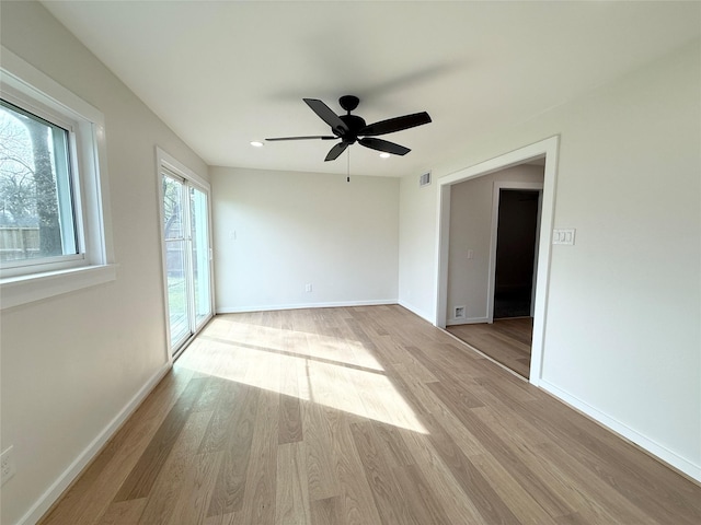 empty room featuring visible vents, wood finished floors, a ceiling fan, and baseboards