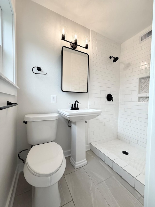 bathroom with a stall shower, baseboards, visible vents, and toilet