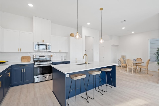 kitchen with tasteful backsplash, visible vents, stainless steel appliances, blue cabinetry, and a sink