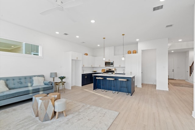 living area featuring recessed lighting, visible vents, light wood-style floors, ceiling fan, and stairs